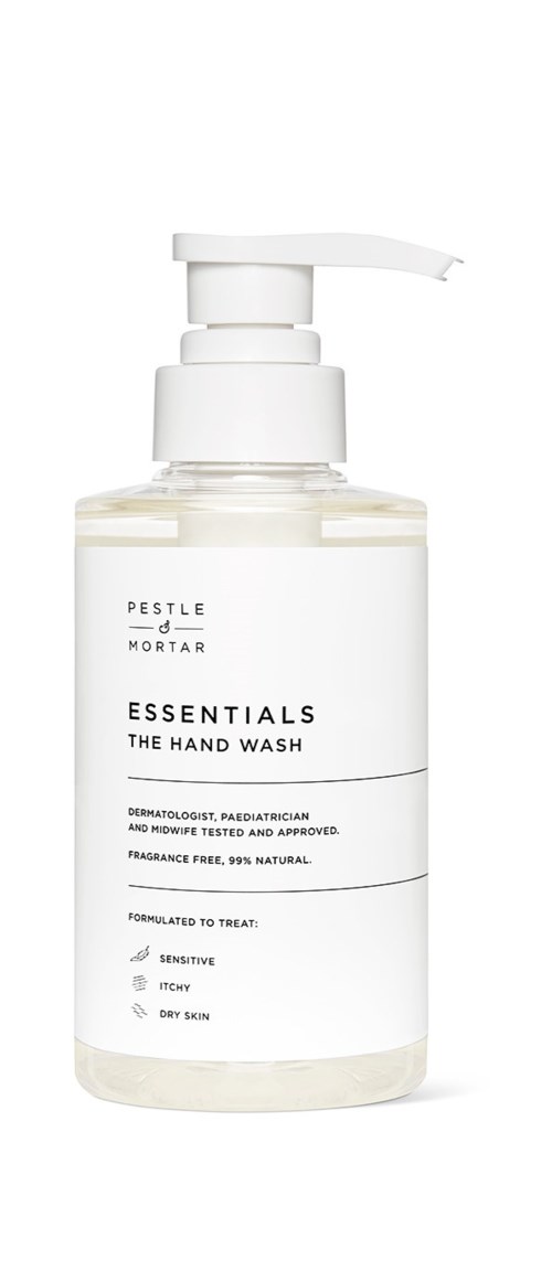 Biała butelka z pompką oznaczona Essentials Hand Wash, przeznaczona dla wrażliwej skóry i naturalnych składników.