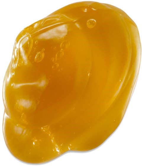 A yellow honey mustard condiment with a smooth, shiny surface and some small bubbles.