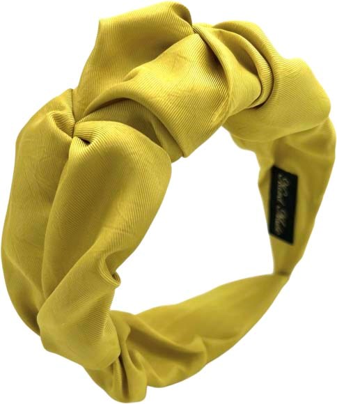 Ein gelber Stoffhaargummi mit einem schwarzen Etikett, wirkt weich und dehnbar, für Haare oder Modeaccessoire.