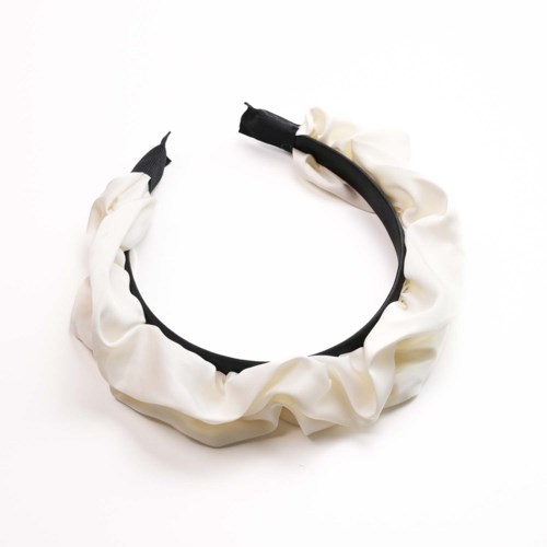 Ein schwarzer Haarschmuck mit weißen Stoffresten. Er hat zwei abgerissene Enden. Der Hintergrund ist weiß.