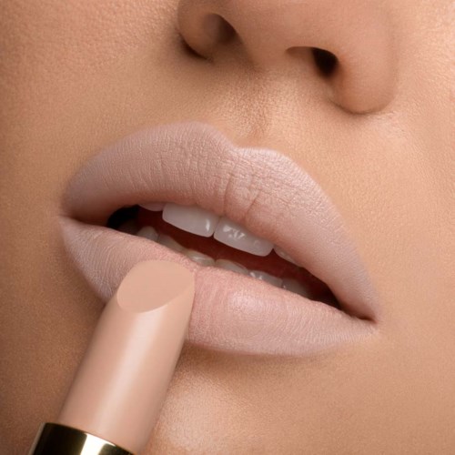 Närbild av läppar med nude look-läppstift, delvis öppna, visar tänder och finger som applicerar läppstift.