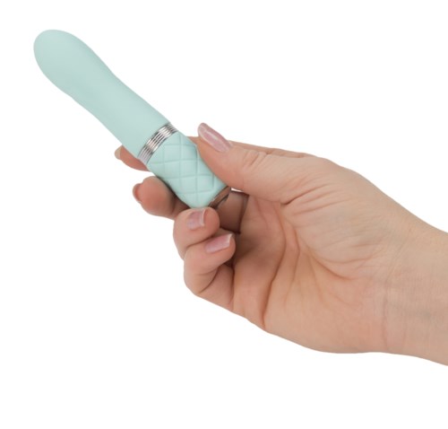 A hand holds a small, light blue vibrator against a plain white background.