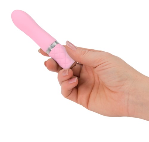 A hand holds a pink vibrator with a silver ring near the middle, against a white background.