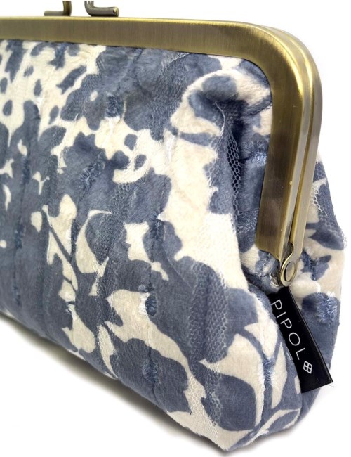 A pouch with a blue and white floral pattern, a brass-colored frame, and a black tag that says "PIPOL."