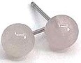 Two light grey buttons with holes, connected by a thin pin, look like part of a sewing or craft project.