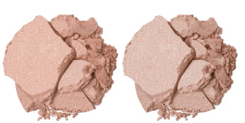 Zwei Stücke zerbrochene rosa Puder-Foundation, verstreut auf schwarzem Hintergrund.