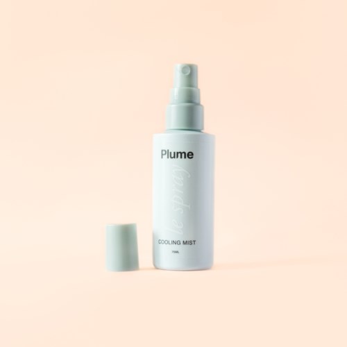 En hvid sprayflaske med etiketten 'Plume' og fjernet låg, mod en lys fersken baggrund.