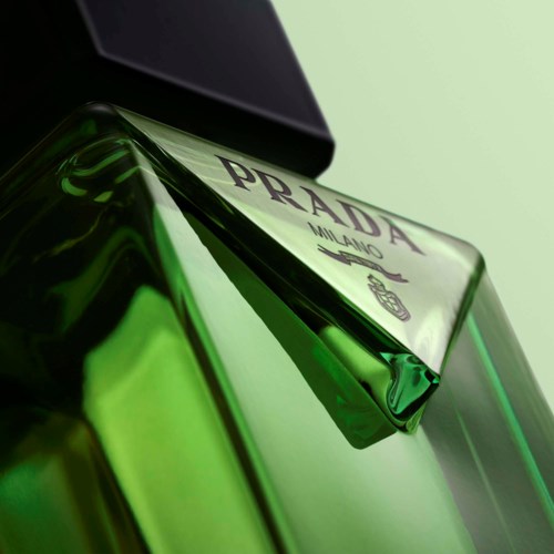 Een groene Prada-parfummat met zwarte dop, leunend tegen een bijpassende doos of deksel.