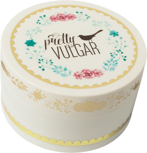 A round box with floral designs, text saying "pretty VULGAR," and a bird silhouette on top.