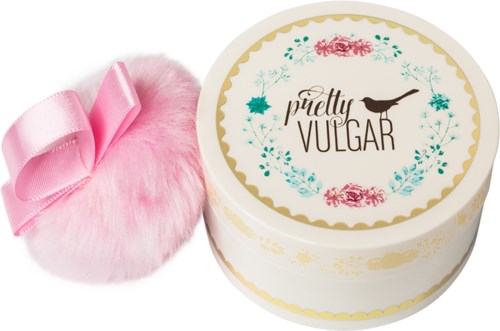 A round container with a floral design and the words "pretty VULGAR" with a bird. A pink fluffy pillow with a ribbon.