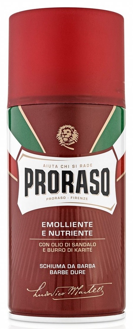 En röd Proraso-flaska med grönt och vitt etikett, innehåller skäggskum med sandelträolja och sheasmör.