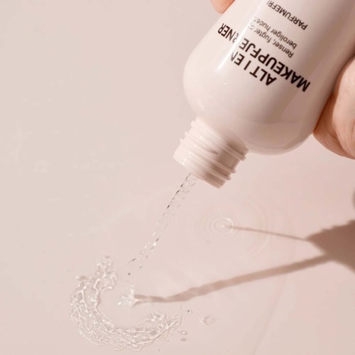 A white bottle labeled ALITTLE MAKEUP REMOVER is pouring clear liquid onto a surface.