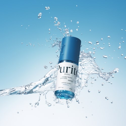 Eine blaue und weiße Hautserumflasche spritzt ins Wasser vor einem klaren Himmel.