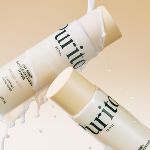 Zwei Flaschen des Hautpflegeprodukts namens Purito liegen auf einer Oberfläche, mit verschütteter Flüssigkeit.