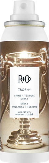 Butelka sprayu oznaczona R+Co Trophy Shine Texture Spray, z wyraźnym obrazem trofeum na etykiecie.