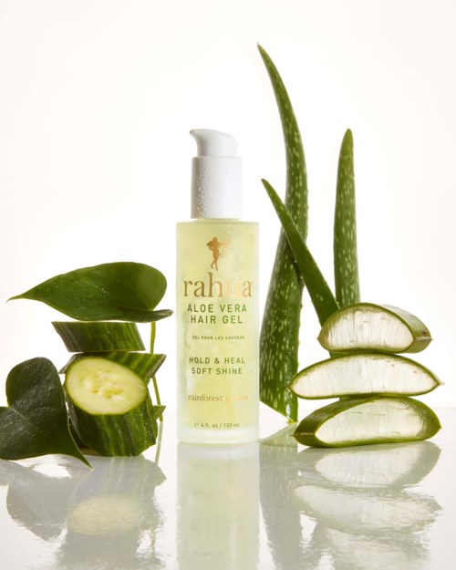 En flaska aloe vera hårgeljack omgiven av aloe vera-skivor och blad på en vit bakgrund.