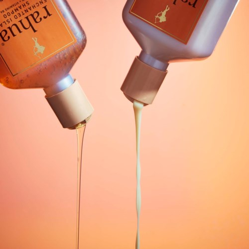 Två flaskor är upp och ner med lotion eller tvål som rinner ut mot en orange bakgrund.
