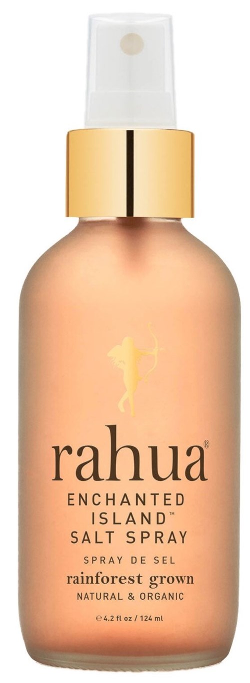 En sprayflaska med guldkapsel och aprikosfärgad kropp, märkt 'Rahua Enchanted Island Salt Spray,' för hårstyling.