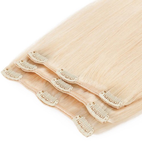 Flera beige hårförlängningar med klämmor är visade, lagda snyggt på en vit bakgrund.