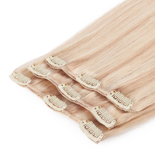 Fyra ljusa hårförlängningar med beige klämmor staplade prydligt.