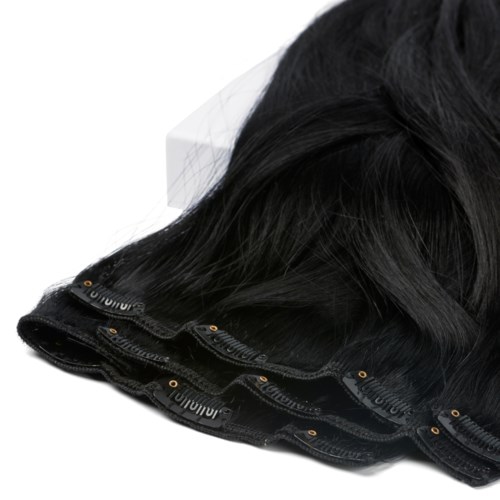 En svart peruk med lace front, delvis lockig och spridd på en vit yta.