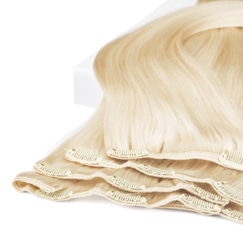 A blonde wig on top of three beige hairnets or caps, arranged in a row.