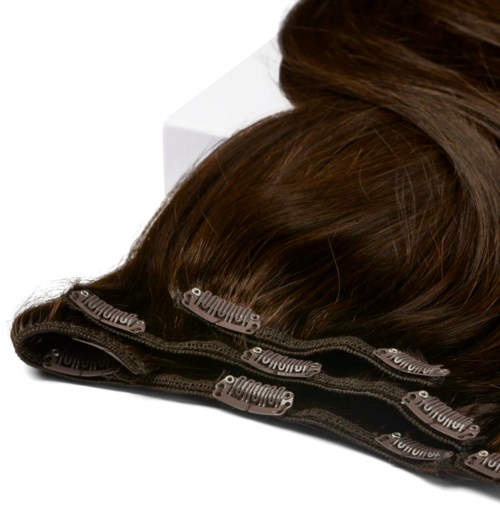 A brown hair extension or wig clip with a black elastic band and metal teeth.