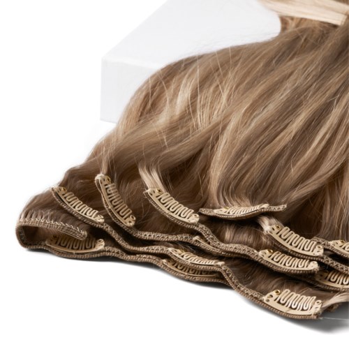 Brown curly hair tied with beige ribbon, resting on a white box.