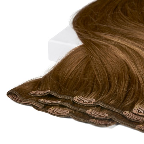 A person's hair is spread over a white surface, with a napkin or cloth underneath. The hair is light brown and wavy.