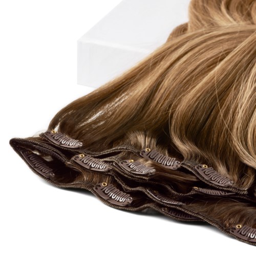 A wig with long, wavy, blonde hair made of synthetic or real hair, styled smoothly and laid out on a flat surface.