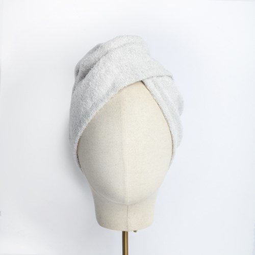 En dockhuvudmannequin med handduk lindad som turban. Enkelt vitt bakgrund. Handduken är noggrant vikt och lindad.