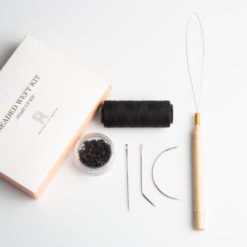 A jewelry making kit with tools, black thread, and beads on a white surface.