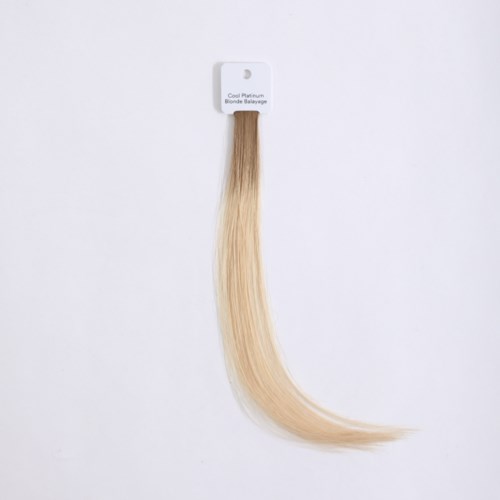 Hårförlängning i ljusblont, fäst på ett vitt kort, märkt 'Cool Platinum Blonde Balayage.'