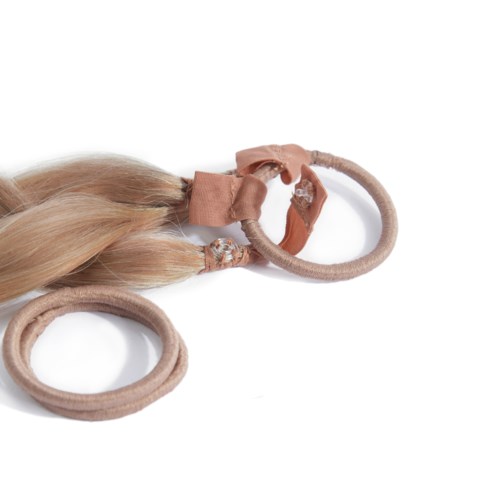 Två hårband med blonda hårförlängningar och en liten rosett. Bandena är beige och håret är glänsande.