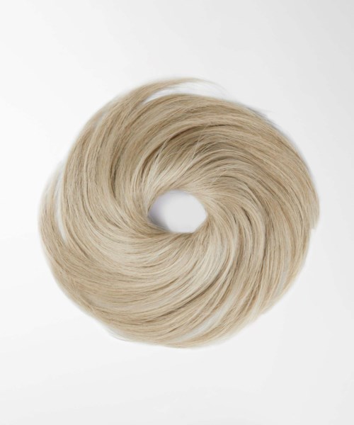 En blond peruk eller hårkudde i en cirkel på en enkel bakgrund.