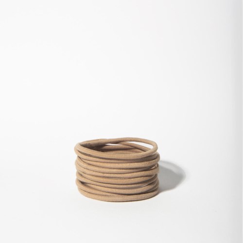 A pile of brown rubber bands is placed on a white background. The bands are stacked randomly and cast a small shadow.