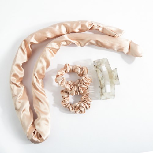 Mjuka sidenaccessoarer, inklusive en lång scarf, en mindre hårsnodd och en hårklämma i marmorliknande material.