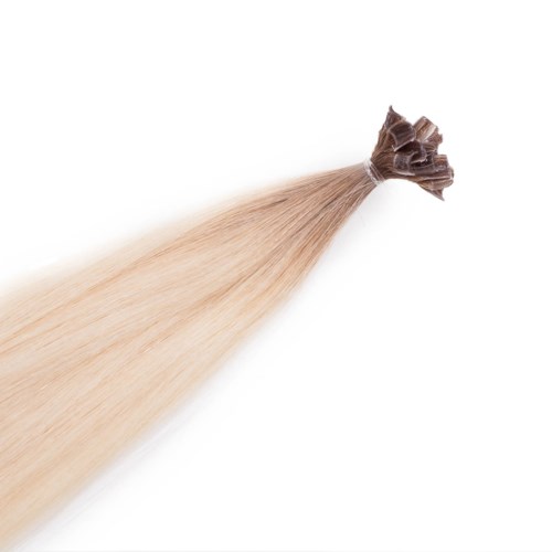 En bunt blont hår bunden upptill, rinner neråt på en vit bakgrund.