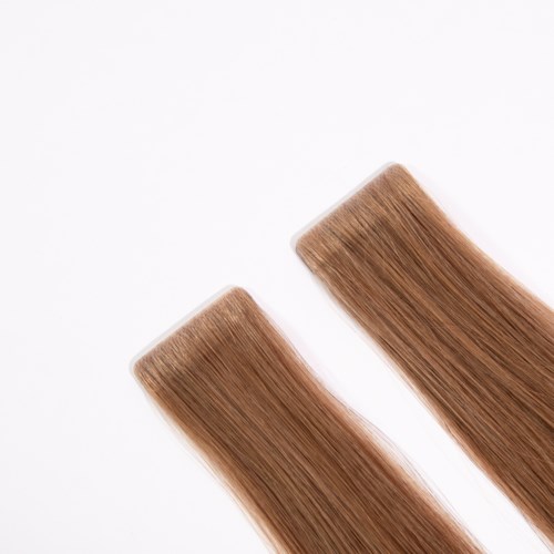 Two light brown hair extensions laid flat on a white background.