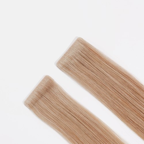Two strands of blonde hair lying parallel on a white surface.