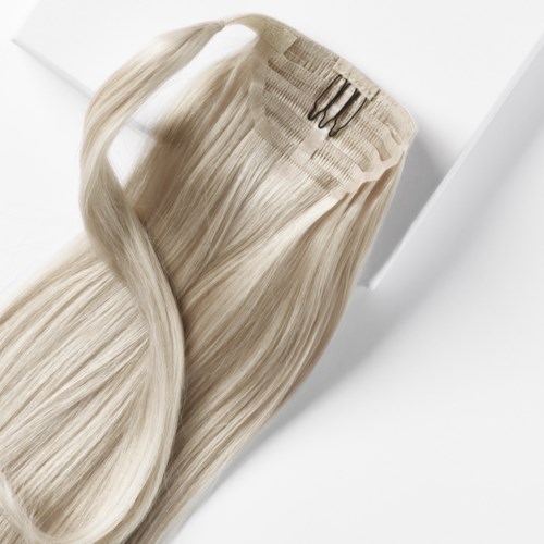 Ljust blont hår med en liten metallgaffel inuti, på vit bakgrund.