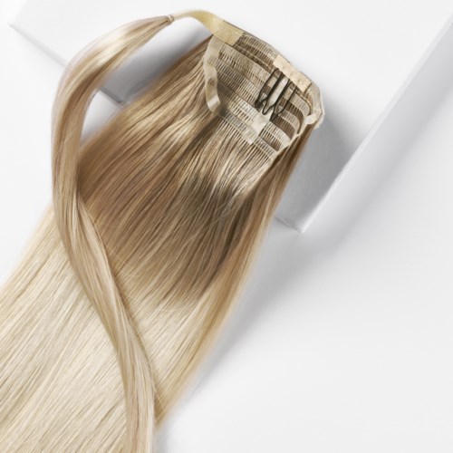Ein Bündel langer, blonder Haarverlängerungen, die an einem Clip-in-Haarteil befestigt sind.