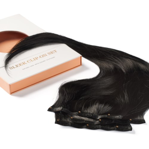 A set of long black hair extensions on a white surface, with a pink box labeled 'Sleek Clip On Set.'