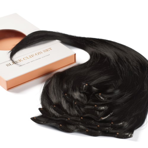 A hair extension set with black hair clips, placed on a white surface next to a box.