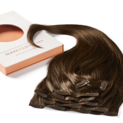 A set of brown hair extensions with clips, placed next to a white and pink box labeled 'Sleek Clip Set.'