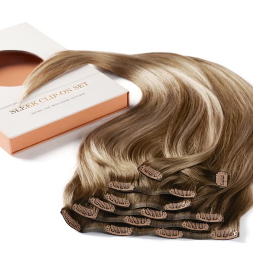 Hiustenpidikkeiden kokonaisuus tai osat, vaaleanruskea väri, asetettuna laatikon viereen. Laatikossa lukee "Sleek Clip-On Set."