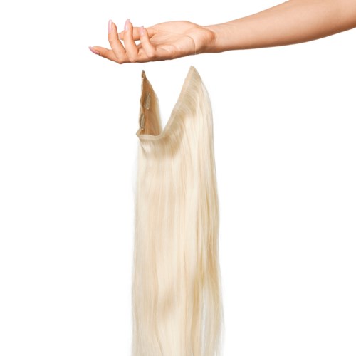 A hand catches a wig with long blonde hair above a white background.