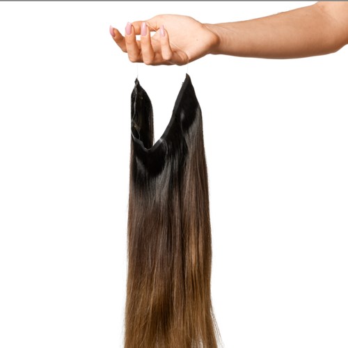 A hand holds a bundle of long, straight, brown-black hair extensions against a white background.