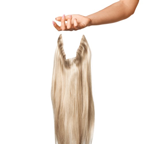 A hand drops long, blonde hair with two pointed hair extensions or clips attached. The background is white.