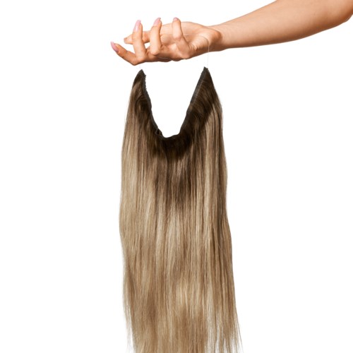A hand holds a hairpiece or wig with long, straight, brown and blonde hair. The background is white.
